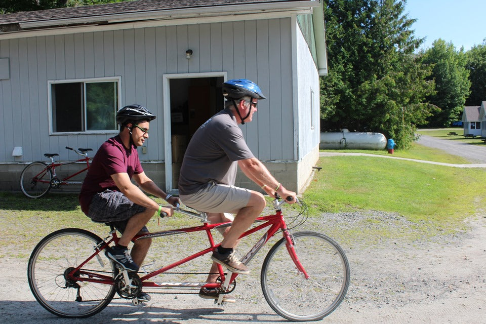 An adult and young person riding a tandem bicycle.
